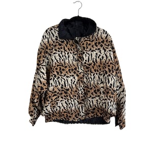 May include: A brown, black, and white leopard print jacket with a black zipper and collar. The jacket is reversible and has a solid black side.