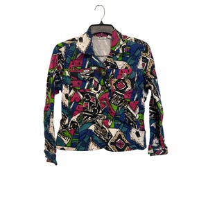 以下が含まれることがあります： 青、ピンク、緑、白の色合いの幾何学模様が特徴的なカラフルなジャケット。 ジャケットは襟付き、ボタン留め、長袖です。 ジャケットは黒いハンガーに吊るされています。