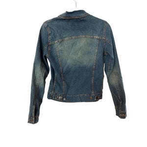 May include: A blue denim jacket with long sleeves and a button closure. The jacket has a classic style and is made of a soft, comfortable material.