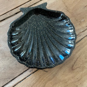 May include: A black seashell-shaped dish with gold glitter embedded in the surface.