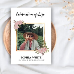 May include: A white card with the words "Celebration of Life" in black script. A photo of a woman in a straw hat and sunglasses is framed in gold. Pink floral accents and the name "SOPHIA WHITE" are also included.