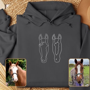May include: A dark gray hoodie with a white outline of two horse heads on the front. The hoodie has a drawstring hood and a kangaroo pocket.
