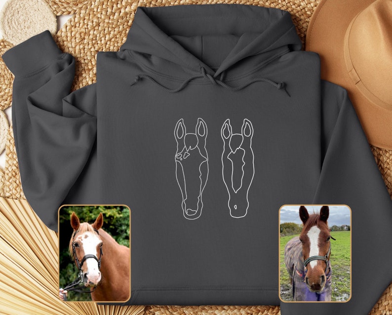 May include: A dark gray hoodie with a white outline of two horse heads on the front. The hoodie has a drawstring hood and a kangaroo pocket.