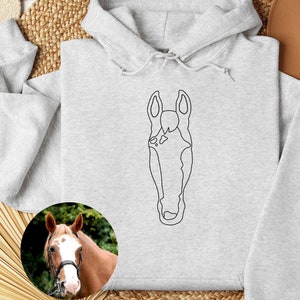 May include: A gray hoodie with a black line drawing of a horse's head on the front. The hoodie has a drawstring hood and a kangaroo pocket.