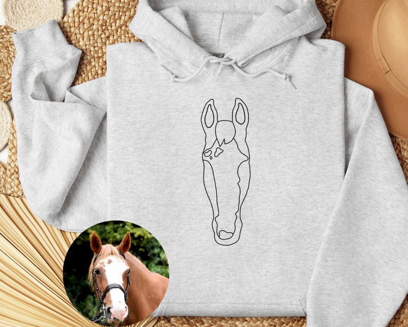 May include: A gray hoodie with a black line drawing of a horse's head on the front. The hoodie has a drawstring hood and a kangaroo pocket.