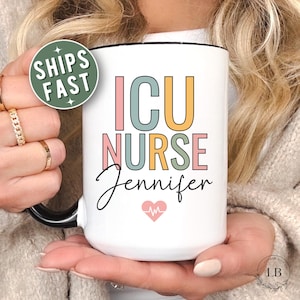 May include: A white ceramic mug with a black handle and the text "But First, Coffee" in a bold, black font. The mug is set against a blurred background, suggesting a cozy setting.