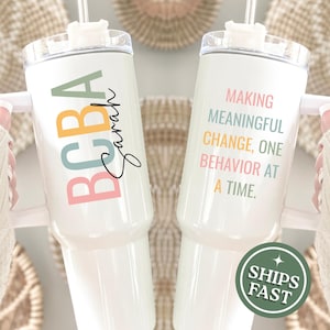 May include: Two white insulated tumblers with handles and straws. One tumbler has the text "BCBA Sarah" in colorful letters. The other tumbler has the text "MAKING MEANINGFUL CHANGE, ONE BEHAVIOR AT A TIME." A green sticker says "SHIPS FAST."