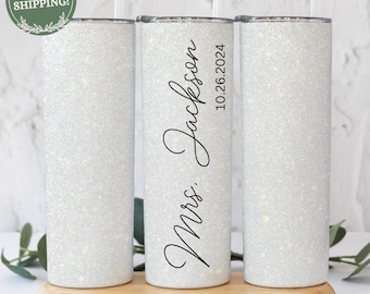 May include: Three white glitter tumbler cups with black text. The middle cup says "Mrs. Jackson 10.26.2024".