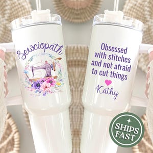May include: White insulated tumbler with a handle, featuring text and graphics. One tumbler says "Sewciopath" with a sewing machine and floral wreath. The other says "Obsessed with stitches and not afraid to cut things" with a heart and name.