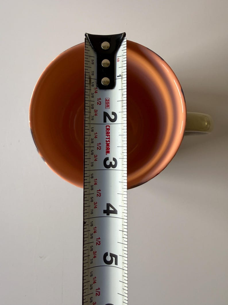 Puede incluir: Vista superior de una taza de color cobre con un asa verde claro. Una cinta m&eacute;trica dentro de la taza indica una medida de aproximadamente 12,7 cm. El interior de la taza tiene un acabado brillante.