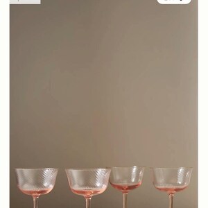 May include: Set of four Vista coupe glasses. Each glass has a pink stem and bowl with a textured, diagonal pattern. The glasses are designed for serving cocktails and other beverages.