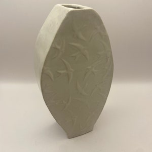 Può includere: Vaso in ceramica bianca di forma ovale con un design in rilievo di uccelli in volo.