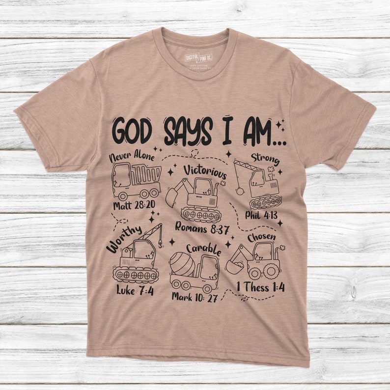 Puede incluir: Una camiseta color beige con la frase "GOD SAYS I AM..." y palabras inspiradoras con referencias b&iacute;blicas, como "Never Alone" y "Victorious". El dise&ntilde;o incluye dibujos lineales de veh&iacute;culos de construcci&oacute;n. La camiseta est&aacute; hecha de un material suave.