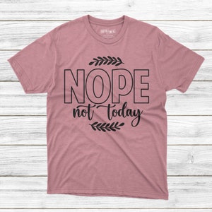 May include: A pink t-shirt with black text that reads "NOPE not today" with a small leafy design above and below the text.
