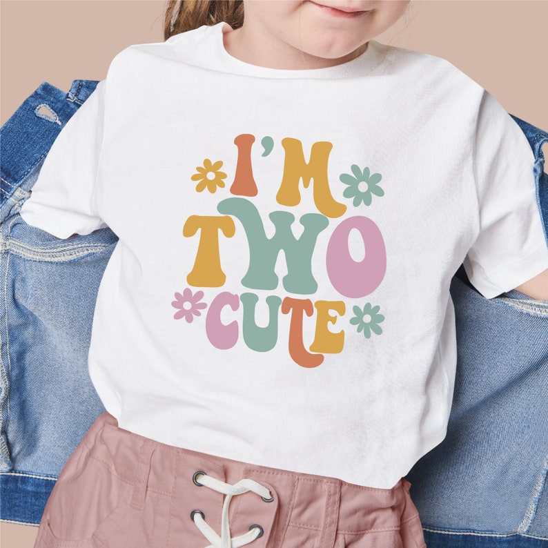 Puede incluir: Camiseta blanca con un gr&aacute;fico colorido que dice "I'm Two Cute" con flores alrededor del texto.