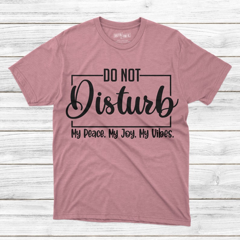 May include: A heather pink t-shirt with black text that reads "DO NOT Disturb My Peace. My Joy. My Vibes."