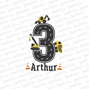 Könnte beinhalten: Eine schwarze Zahl drei mit einem gelben Bauwagen, einem Kran und einem Bagger auf einem Straßen-Design. Der Name Arthur ist unter der Zahl mit zwei orangefarbenen Verkehrskegeln geschrieben.