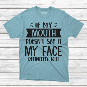 May include: A light blue t-shirt with black text that reads "If my mouth doesn't say it my face definitely will."