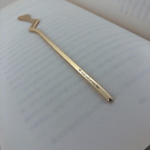 Op de afbeelding: Gouden bladwijzer met een unieke vorm en de inscriptie "The truth will set you free".