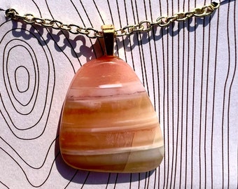 May include: A gold chain necklace with a pendant made of a large, light pink, white, and brown agate stone.