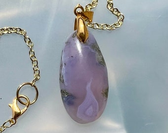 May include: A gold chain necklace with a purple and grey agate pendant. The pendant is a teardrop shape and has a gold bail.