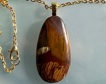 May include: A gold chain necklace with a teardrop-shaped pendant made of brown and white agate.