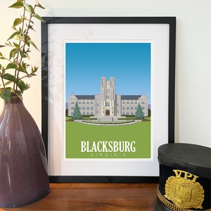 Pode incluir: Uma impressão emoldurada de um edifício cinza com céu azul e grama verde. O edifício tem uma inscrição branca que diz "BLACKSBURG VIRGINIA".