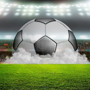 Può includere: Un pallone da calcio bianco e nero si trova al centro di un campo erboso verde. Il pallone è circondato da fumo bianco e lo sfondo è un'immagine sfocata di uno stadio con luci.