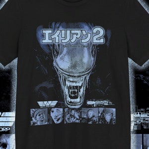 May include: Black t-shirt featuring a graphic print of the Alien 2 movie poster. The poster depicts the alien creature with the text "エイリアン2" and "This Time It's War".