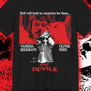 Puede incluir: Camiseta negra con un gráfico rojo y blanco de un póster de película para "Los Demonios". El póster presenta a Vanessa Redgrave y Oliver Reed. El texto en el póster dice "El infierno no les deparará sorpresas..."