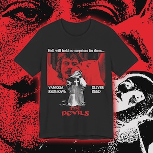 Könnte beinhalten: Schwarzes T-Shirt mit einem Filmposter-Design. Das Design enthält den Text "Hell will hold no surprises for them...", die Namen "Vanessa Redgrave" und "Oliver Reed" sowie den Titel "The Devils" in Rot.