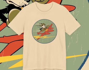 May include: Beige t-shirt featuring a vintage cartoon graphic of a pilot in a red airplane with a yellow lightning bolt. The graphic is inside a blue-bordered circle. A cartoon character is visible in the background.