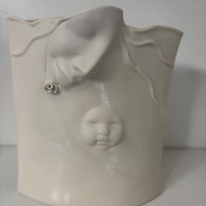May include: A cream-colored ceramic vase with a unique design. The vase features a sculpted face and a small rose. The vase has a curved shape and a smooth, glossy finish. The vase is a decorative item.
