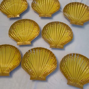 May include: Set of eight yellow ceramic shell-shaped plates with red dots. The plates are perfect for serving appetizers or desserts.