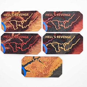 May include: Five wooden tiles with a map design and the text "Hell's Revenge" printed on each tile. The tiles are in different color variations with red, orange, yellow, and black accents.