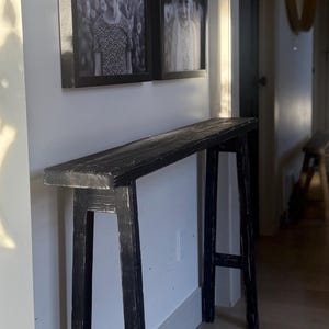 Könnte beinhalten: Eine weiße Keramik-Tasse mit schwarzem Henkel und dem Text "But First, Coffee" in schwarzer, fetter Schrift. Die Tasse steht auf einer Holzoberfläche.