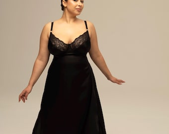 May include: A floor-length black nightgown featuring a satin-finish fabric and a lace-trimmed bodice. The garment includes thin shoulder straps and a scoop neckline, with a flowing skirt that extends to the floor, creating a simple silhouette.