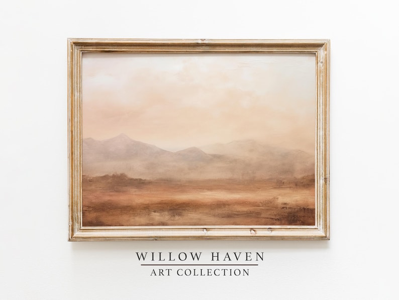May include: A framed landscape painting with a warm color palette. The artwork depicts a mountain range in shades of brown, beige, and orange, with a hazy sky. The frame is a light, distressed wood. The text "WILLOW HAVEN ART COLLECTION" is at the bottom.