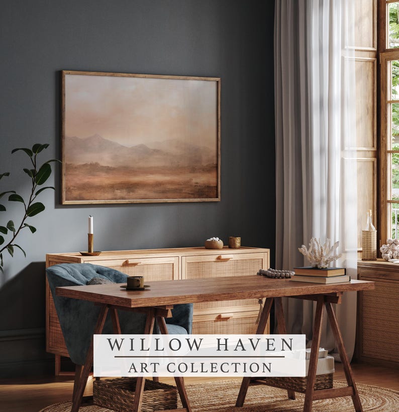 May include: A framed landscape painting in warm earth tones hangs above a wooden cabinet. A wooden desk and blue chair are in front of the cabinet. The text "WILLOW HAVEN ART COLLECTION" is displayed on a white banner.