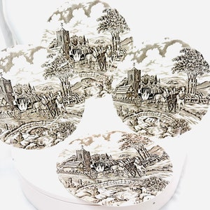 May include: Set of four brown and white ceramic plates with a vintage design featuring a horse-drawn carriage, a church, and trees. The plates are round and have a raised rim.