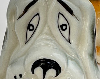 A vintage anthropomorphic basset hound droopy dog ceramic figurine, tan and black dog with big eyes and droopy ears