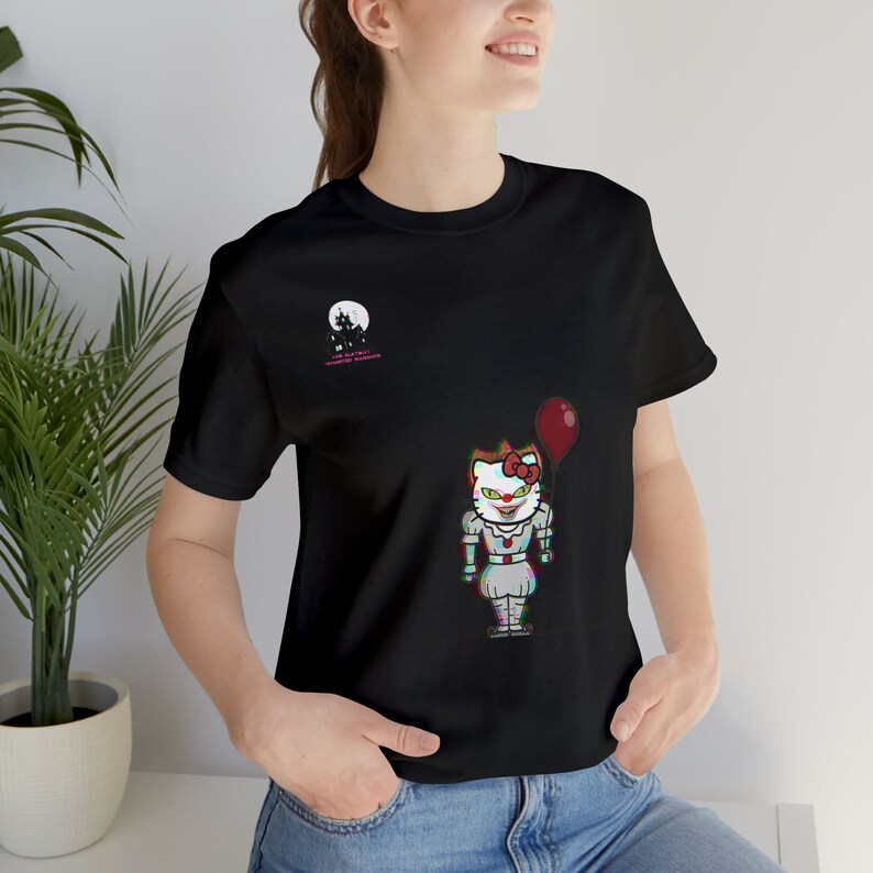 K&ouml;nnte beinhalten: Schwarzes T-Shirt mit einem Cartoon-Charakter, einer Mischung aus Hello Kitty und einem Clown, der einen roten Ballon h&auml;lt. Das Shirt hat auch eine Vollmond-Grafik und Text. Das Design hat einen Glitch-Effekt.
