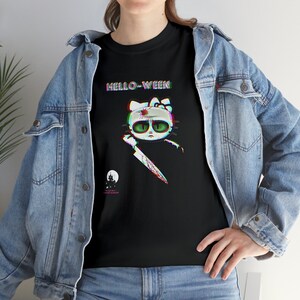 May include: Black t-shirt with a cartoon cat design, green eyes, and a bloody knife. The text "HELLO-WEEN" is above the cat, with a haunted house and moon graphic below. The shirt is worn with a denim jacket.