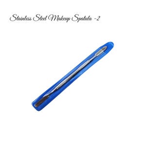 May include: A stainless steel makeup spatula with two ends, one flat and one pointed, in a blue plastic sleeve.  The spatula is used for applying and blending makeup.