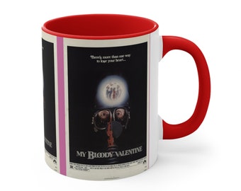 Può includere: Tazza da caffè in ceramica bianca con interno e manico rossi. La tazza presenta una locandina di film vintage per il film horror "My Bloody Valentine" con un assassino mascherato e il testo "C'è più di un modo per perdere il cuore..."