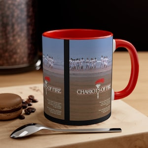 May include: A red and black coffee mug with a picture of a group of people running on a beach. The mug has the text "Chariots of Fire" on it. The text below the image reads "This is a story of fast men who ran, not to win, but to give something to the world. They had to achieve anything. Except their goal. Each their own way."