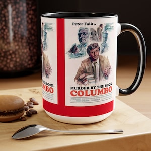 May include: A white ceramic mug with a black handle and rim. The mug features a vintage movie poster design for the TV show "Columbo" with the title "Murder by the Book" and the actor Peter Falk's name. The poster is in red, white, and blue colours.