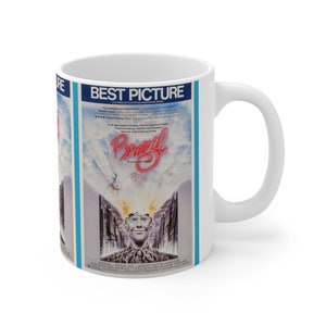 Może przedstawiać: Biały ceramiczny kubek z plakatem filmowym "Brazil". Plakat przedstawia tytuł filmu w czerwonym skrypcie, twarz mężczyzny i słowa "Best Picture". Kubek ma zakrzywiony uchwyt i jest przeznaczony do gorących napojów.