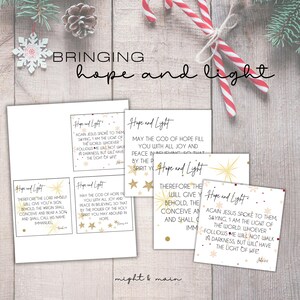 Könnte beinhalten: Eine Sammlung weißer Karten mit goldenen Sternen und Schneeflocken, die die Worte "Hope and Light" und inspirierende Zitate tragen. Das Bild enthält den Text "Bringing hope and light" und den Markennamen "might & main".