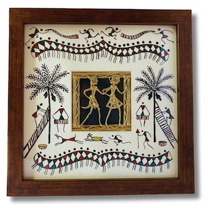 May include: A framed artwork featuring a traditional Indian folk art style. The artwork depicts a scene with two figures dancing in the center, surrounded by palm trees, animals, and geometric patterns. The artwork is framed in a brown wooden frame.